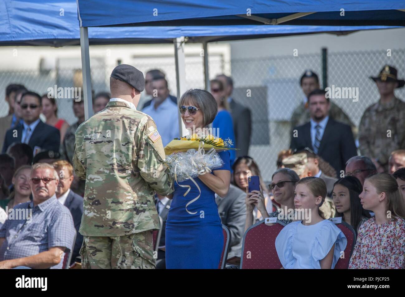 Ansbach, Germany -- A U.S. Soldier presents yellow roses to Mrs. Ingrid Pierce, wife of the incoming United States Army Garrison commander Col. Steven M. Pierce during the Change of Command ceremony at Barton Barracks parade field in Ansbach, Germany, July 18, 2018. Stock Photo