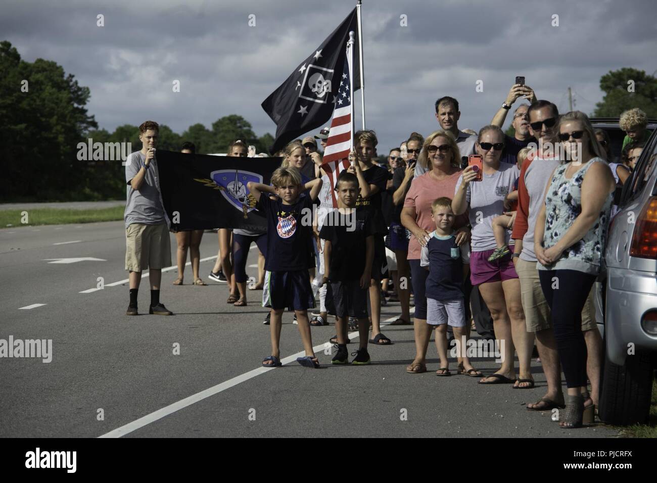 Community members and family and friends of the seven U.S. Marine Raiders and nine Marine Aviator crew members who died in the July, 2017, KC-130 crash in Laflore County, Miss., watch as the Rucking Raiders hike on the shoulder of US-17 in Jacksonville, N.C., during a 900-mile memorial hike from Itta Bena, Miss., to Stump Sound Park, Sneads Ferry, N.C., July 24. 10 teams took turns hiking a continuous 24 hours until reaching Stump Sound Park, but the final stretch finished at the MARSOC Compound on MCB Camp Lejeune. Stock Photo