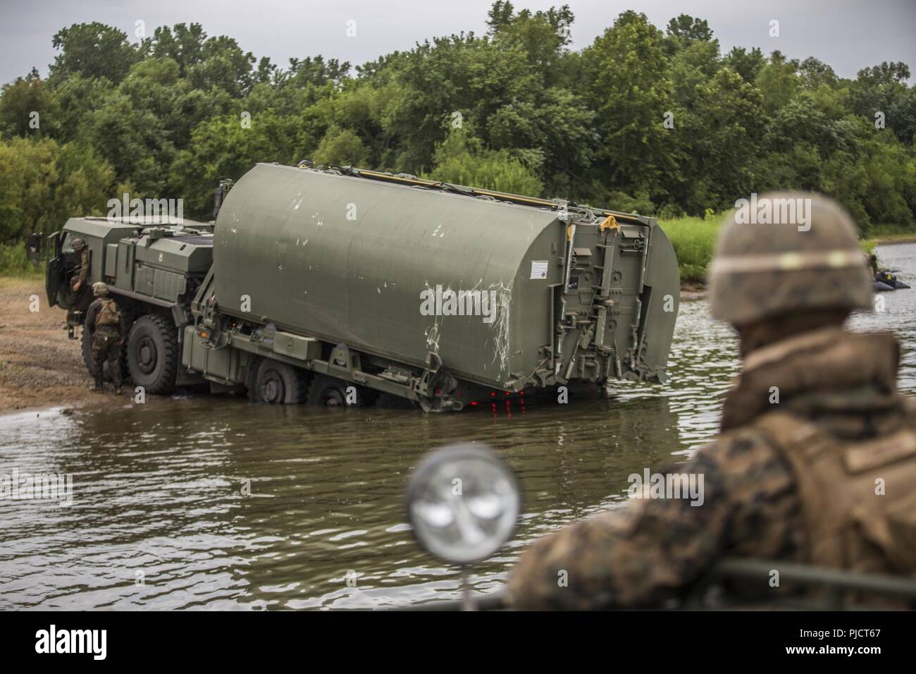 U.S. Marines with Bridge Company, 7th Engineer Support Battalion, 1st Marine Logistics Group, use a Logistics Vehicle System Replacement truck to drop bridge bays in the Arkansas River at Fort Chaffee, Ark., July 18, 2018. The culminating event at the end of River Assault 2018 was a 45-bay continuous span bridge across the Arkansas River. Stock Photo