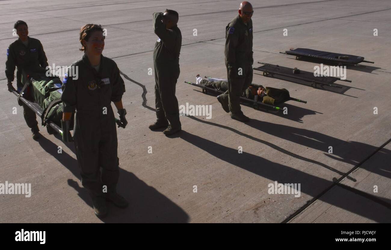 932nd Aeromedical Evacuation Squadron medical members load an early morning flight, as shadows stretch across the runway.  Members make final arrangements to carry medical equipment up a ramp, as they work together with ground crew, preparing to fly with 'simulated patients' during a training flight, July 21, 2018 at Scott Air Force Base, Ill. The AES trained alongside fellow nurses and medical technicians on a multi day flight aboard a C-130 aircraft visiting from the 910th Airlift Wing of Youngstown, Ohio. The 932nd Airlift Wing is a 22nd Air Force unit, under the Air Force Reserve Command,  Stock Photo