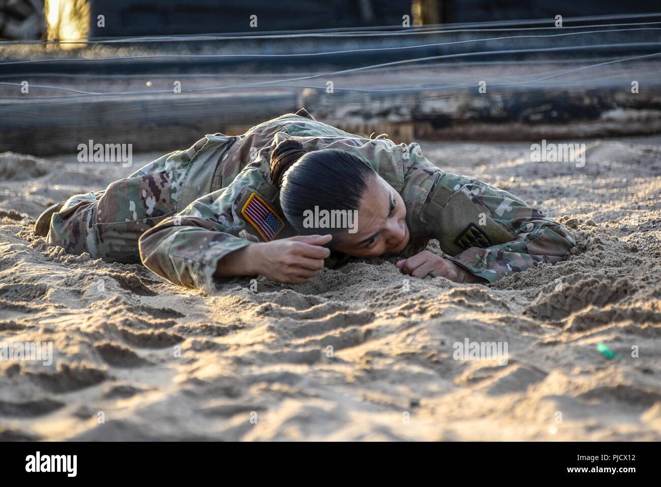 Sgt. Jasminemari Larson, a unit supply specialist for 32d AAMDC, HHB, low crawled through the sand while keeping one dead leg during the Air Assault Obstacle course July 20, 2018. (By Sgt. La’Shawna Custom, 32d AAMDC Public Affairs NCO) Stock Photo