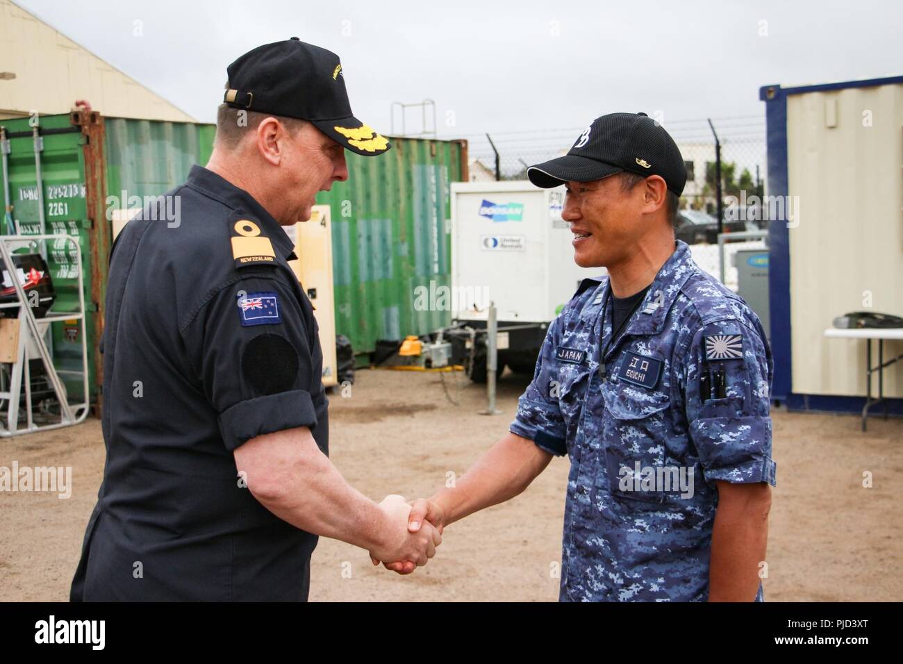 NAVAL BASE POINT LOMA, Calif.  (July 17, 2018) - Royal New Zealand Navy (RNZN) Commodore Tony Millar, maritime component commander and representative of the Chief of Navy (New Zealand), shakes hands with an officer from the Japan Maritime Self Defense Force serving with Mine Warfare Task Force during a visit to Naval Base Point Loma July 17. Millar visited the undersea mine countermeasures task group led by the RNZN during their participation in the Rim of the Pacific (RIMPAC) exercise  in the Southern California area of operations. Twenty-five nations, 46 ships, five submarines, about 200 air Stock Photo
