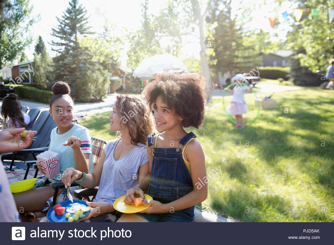 Neighbors eating at summer neighborhood block party in sunny park Stock
