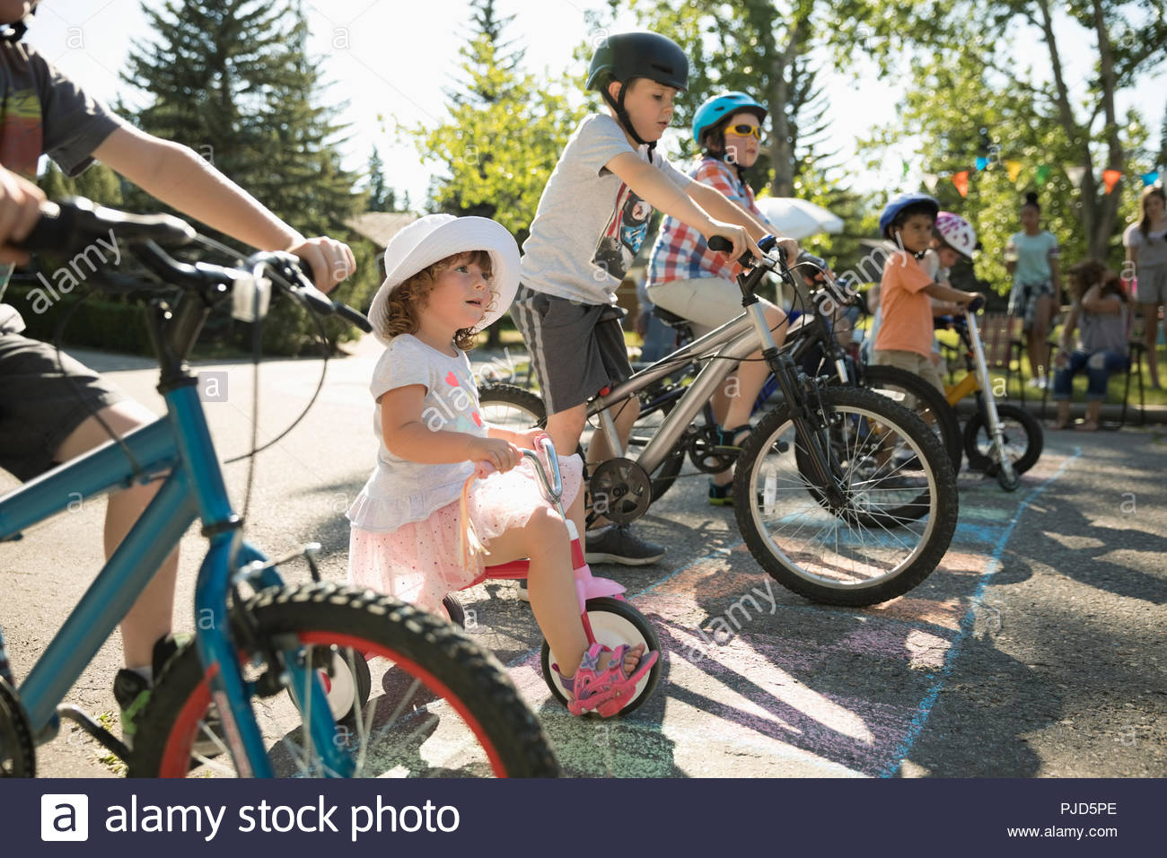 Kids on bicycles ready for race at starting line at summer neighborhood ...