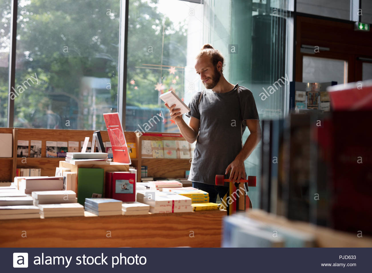 Man with skateboard shopping in bookstore Stock Photo