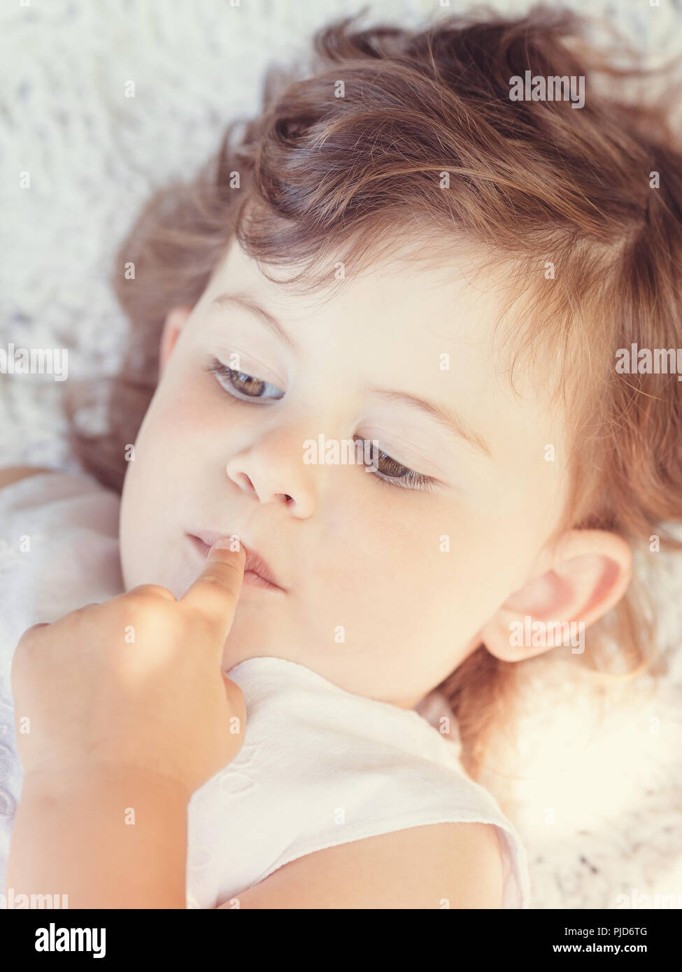 Closeup portrait of a cute adorable child girl laying on white blanket
