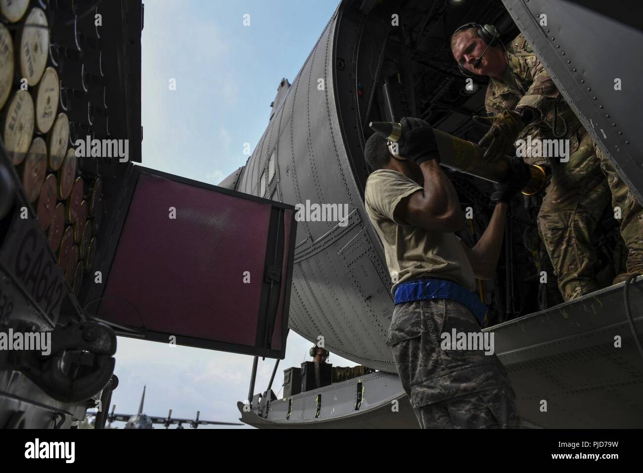 A munitions systems technician with the 1st Special Operations Maintenance Squadron transfers 105 mm high-explosive rounds from storage to U.S. Air Force Tech. Sgt. Brett Laswell, a special missions aviator and evaluator with the 4th Special Operations Squadron, July 18, 2018, at Hurlburt Field, Florida. Aircrew with the 4th SOS conducted a live-fire training mission to sharpen combat-related skills and ensure readiness. Stock Photo