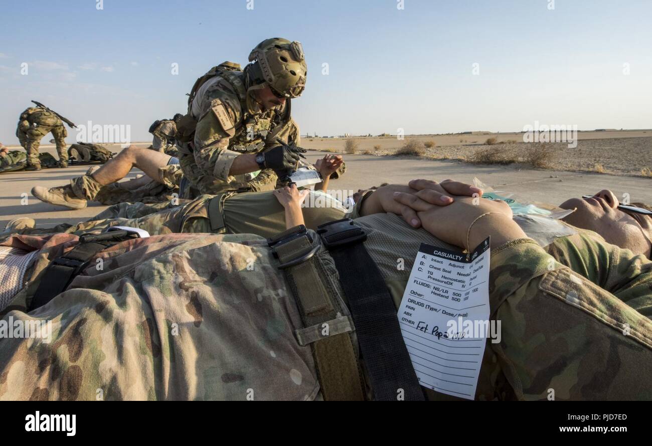A Battlefield Airman assigned to the 52nd Expeditionary Rescue Squadron fills out survivors' causality cards on exercise role players to inform medics of their simulated injuries after an aircraft crash scenario during a combat search and rescue (CSAR) training exercise at a dirt landing strip in Iraq, July 15, 2018. The CSAR exercise was conducted to help validate required training to perform mission taskings and utilization of the various assets on a large scale. Battlefield Airmen assigned throughout the combined joint operational area conduct operations in support of Combined Joint Task Fo Stock Photo