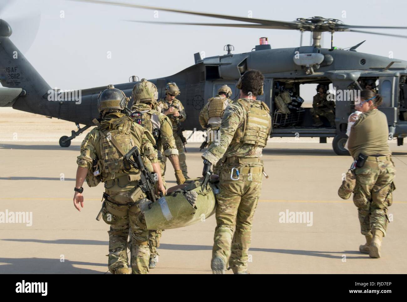 Battlefield Airmen assigned to the 52nd Expeditionary Rescue Squadron transport exercise role players to an HH-60 Pave Hawk assigned to the 46th Expeditionary Rescue Squadron after a simulated aircraft crash during a combat search and rescue training (CSAR) exercise at a dirt landing strip in Iraq, July 15, 2018. The CSAR exercise was conducted to help validate required training to perform mission taskings and utilization of the various assets on a large scale. Battlefield Airmen assigned throughout the combined joint operational area conduct operations in support of Combined Joint Task Force  Stock Photo