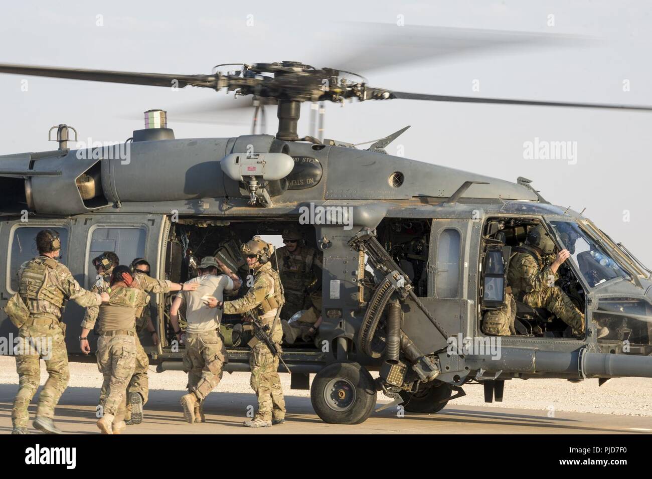 Battlefield Airmen assigned to the 52nd Expeditionary Rescue Squadron transport exercise players to an HH-60 Pave Hawk assigned to the 46th Expeditionary Rescue Squadron after a simulated aircraft crash during a combat search and rescue (CSAR) training exercise at a dirt landing strip in Iraq, July 15, 2018. The CSAR exercise was conducted to help validate required training to perform mission taskings and utilization of the various assets on a large scale. Battlefield Airmen assigned throughout the combined joint operational area conduct operations in support of Combined Joint Task Force - Ope Stock Photo