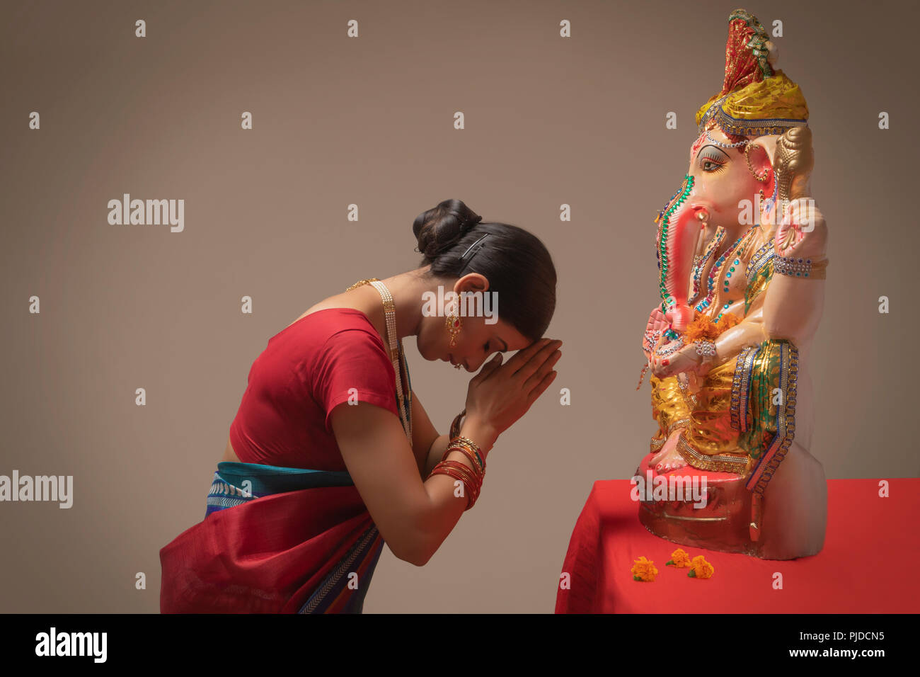 Woman praying with hands joined and eyes closed in front of Ganpati Idol. Stock Photo