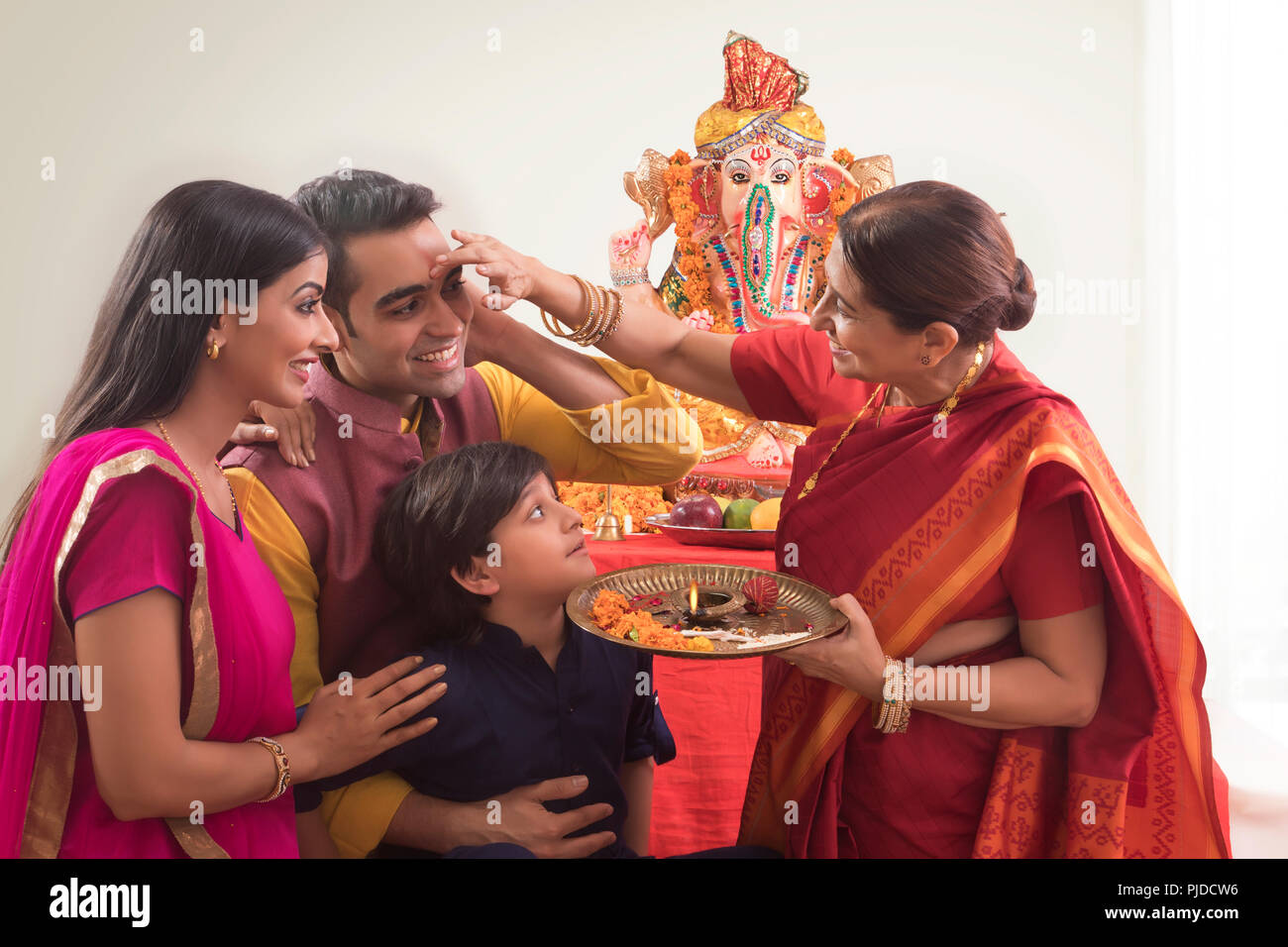 Family celerating ganesh chaturthi where grandmother applies tilak to everybody. Stock Photo