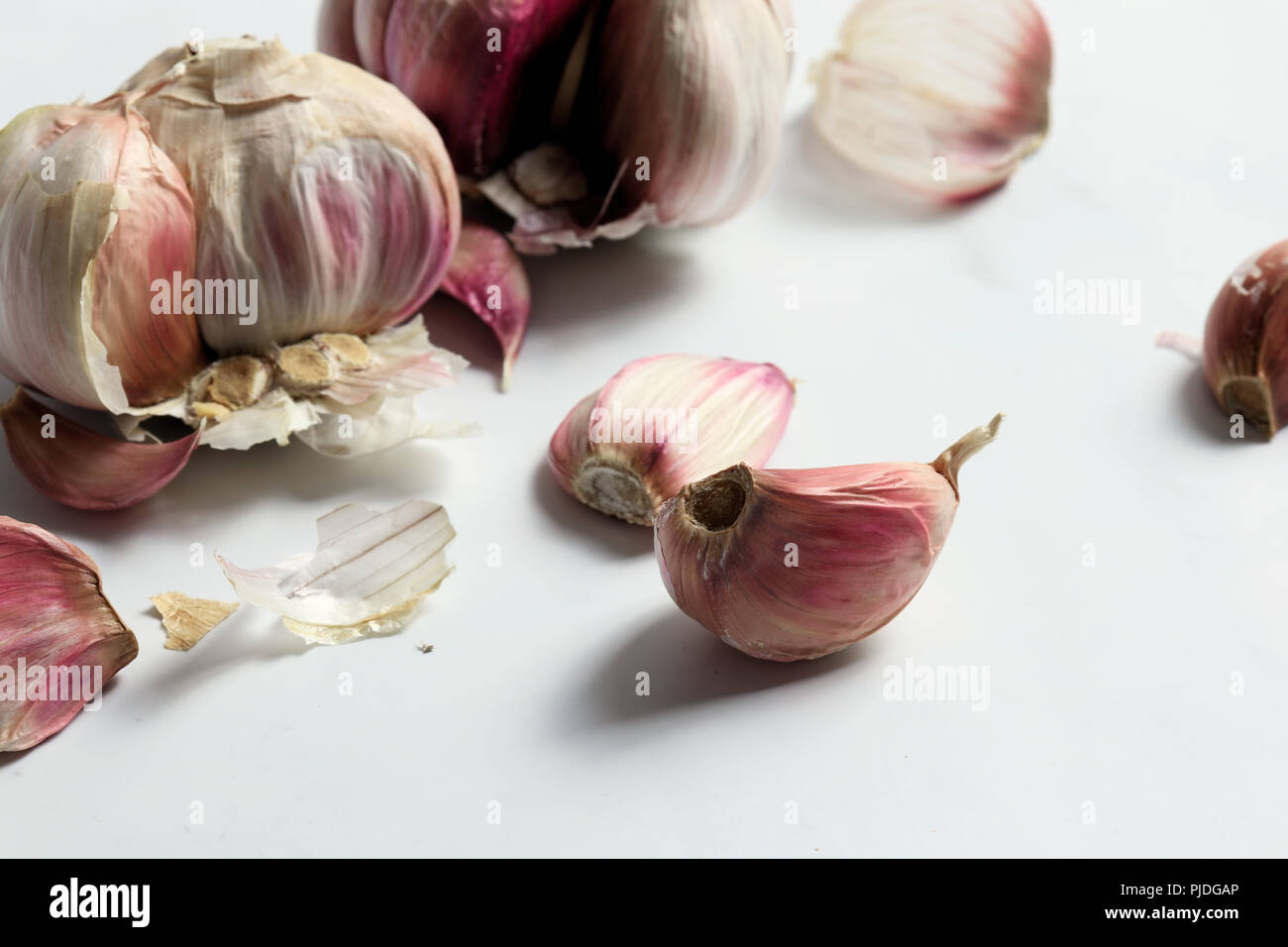 Garlic heads and cloves on white marble surface Stock Photo - Alamy