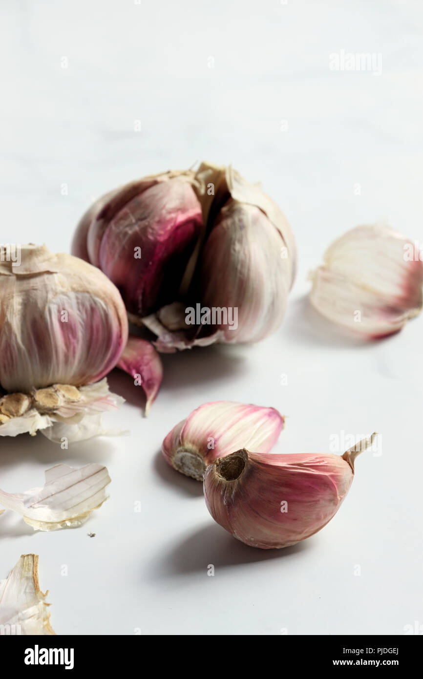 Garlic heads and cloves on white marble surface Stock Photo - Alamy