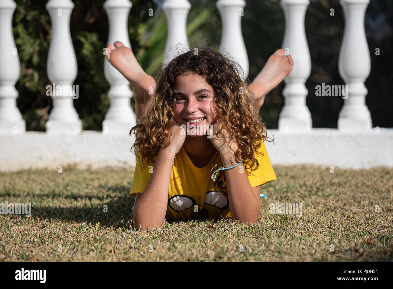 10 year old girl posing lying in the garden of her house and playing with her legs Stock Photo