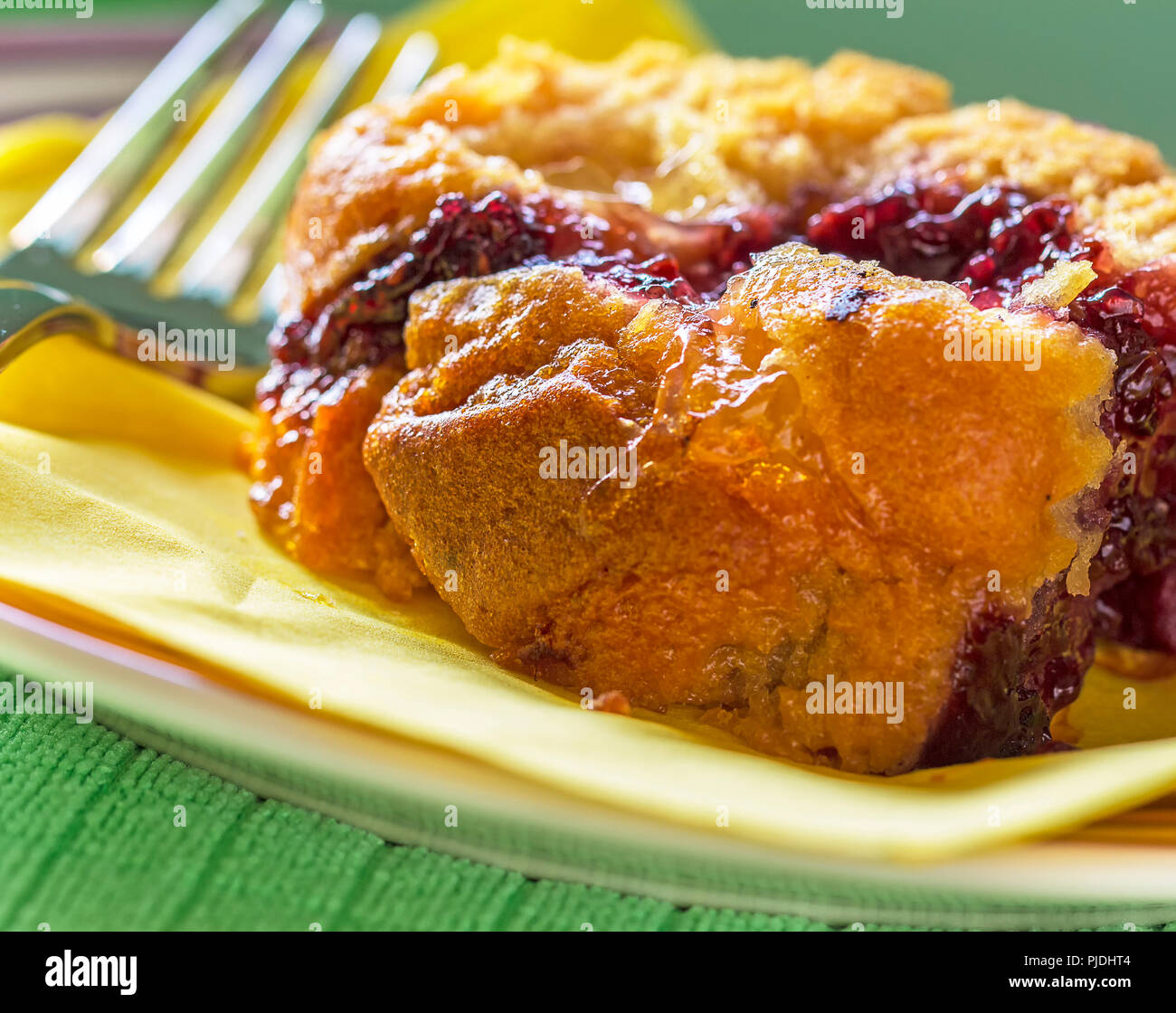Lemon and raspberry cake on a yellow serviette with out of focus fork. Stock Photo