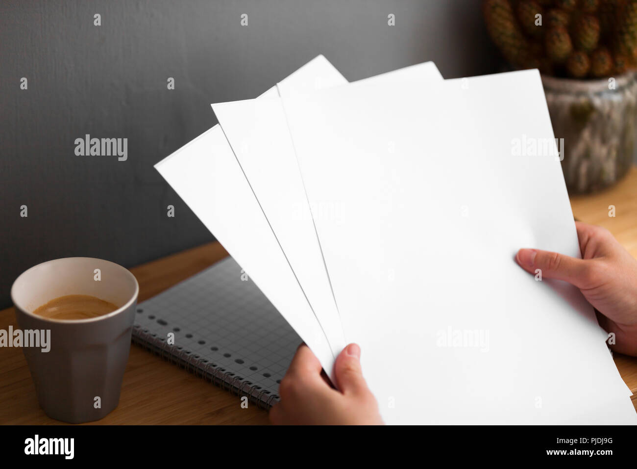 A coffee on desk in home office sorting papers. Stock Photo