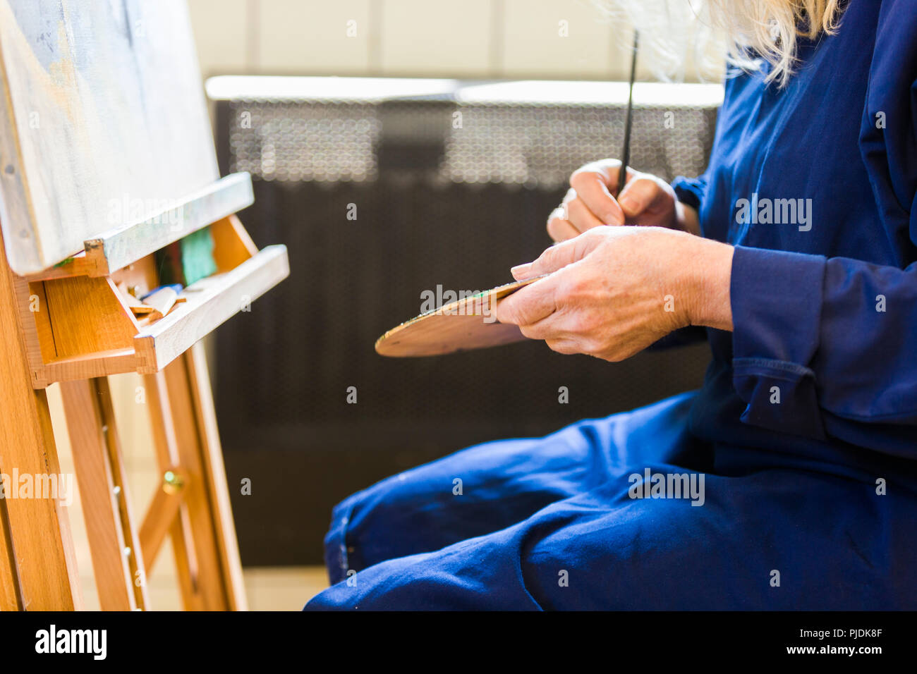 An artist mixing paint on her palette. Stock Photo