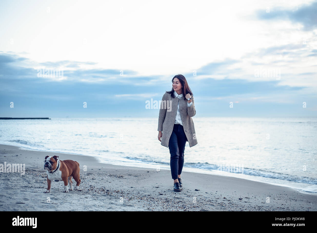 Young woman walking along beach with pet dog Stock Photo