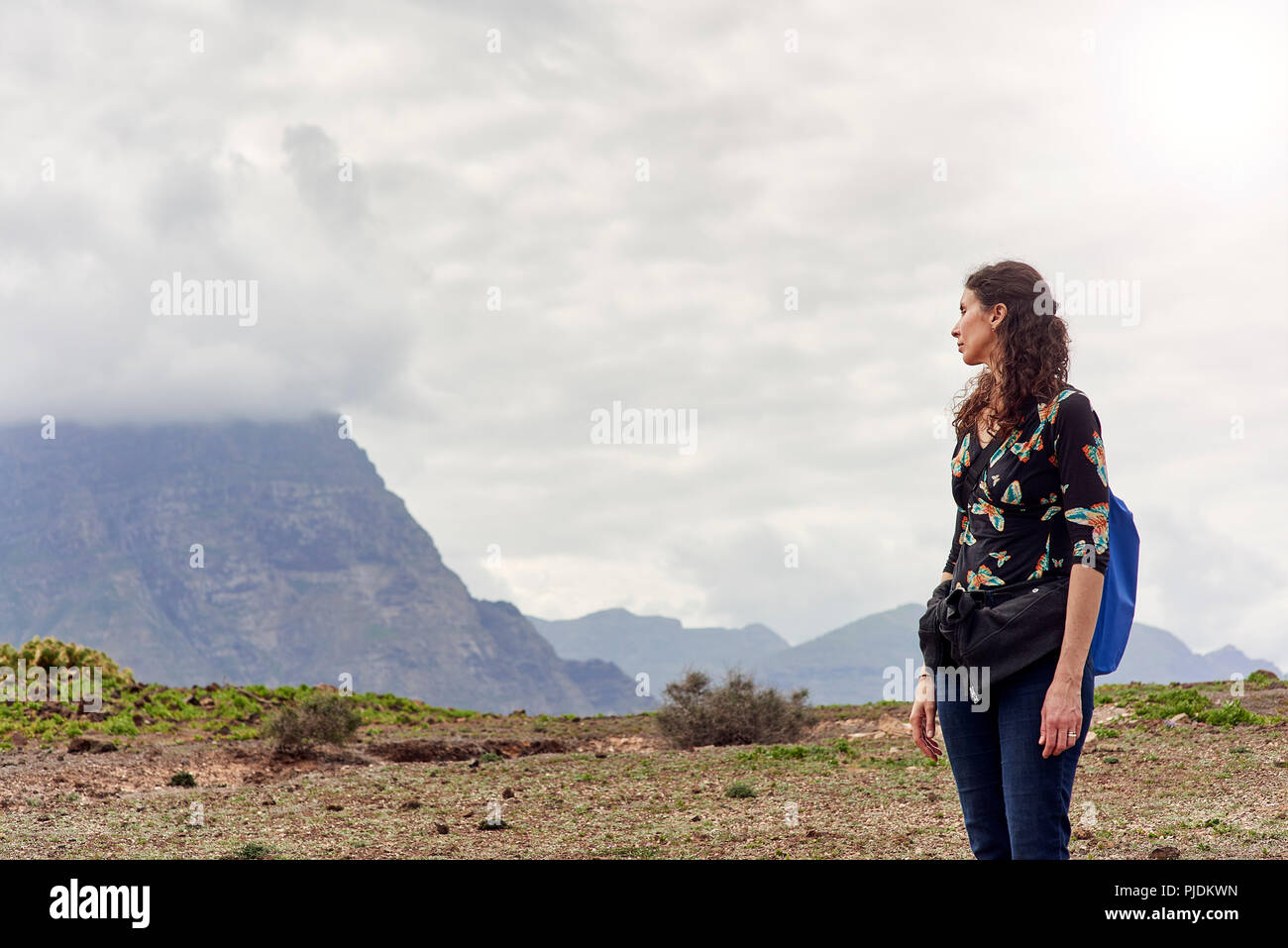 Woman looking out toward low cloud over mountains, Las Palmas, Gran Canaria, Canary Islands, Spain Stock Photo