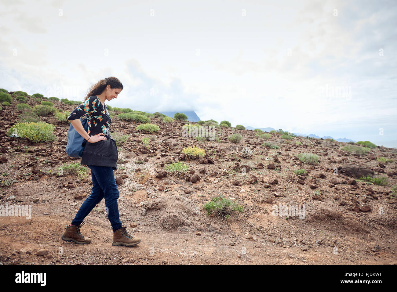 Woman hiking on dirt track in arid landscape, Las Palmas, Gran Canaria, Canary Islands, Spain Stock Photo