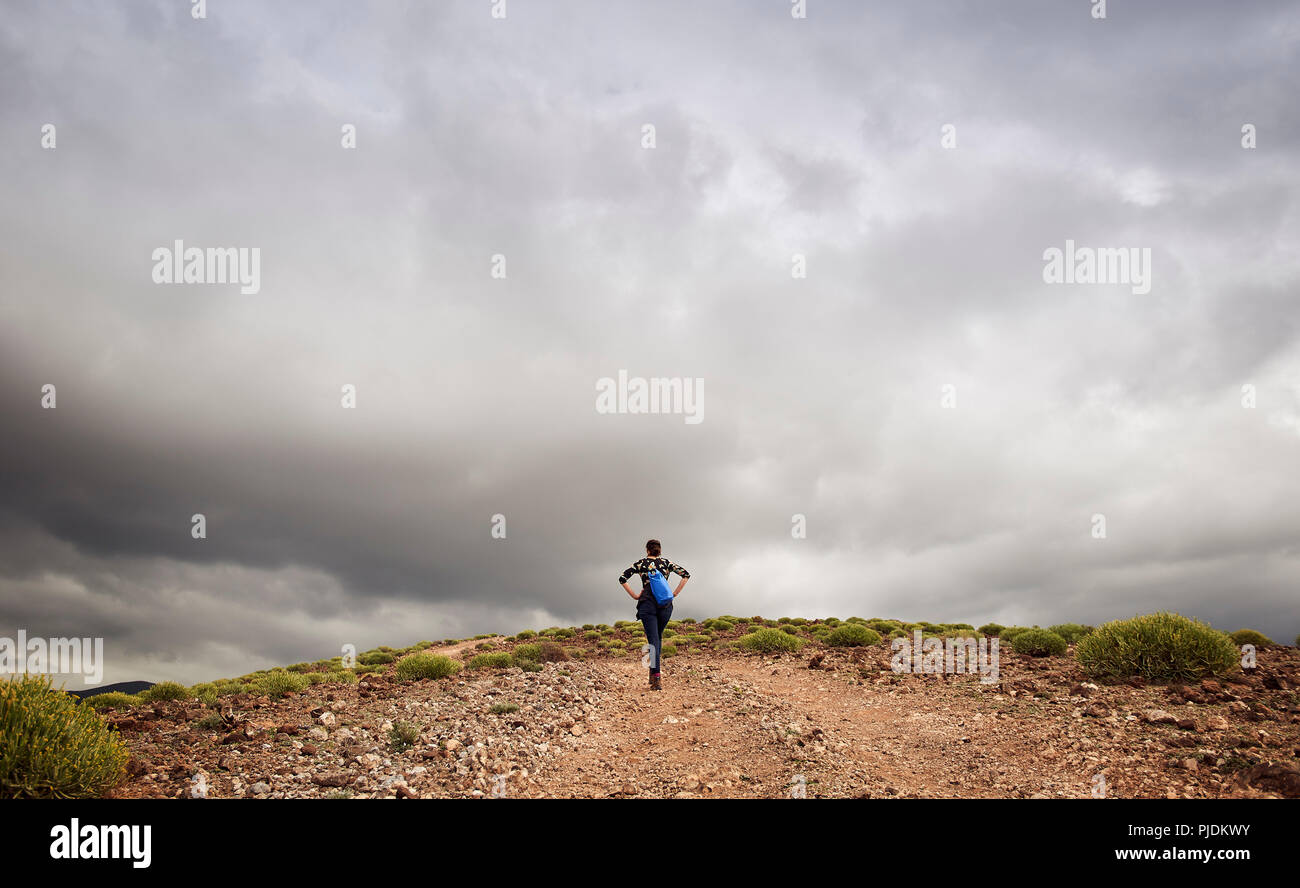 Woman hiking up hill on dirt track, rear view, Las Palmas, Gran Canaria, Canary Islands, Spain Stock Photo