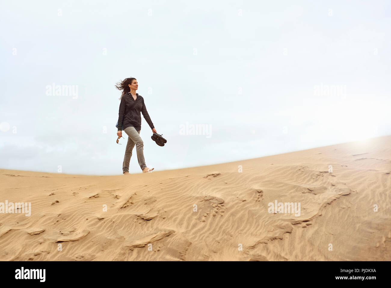Female tourist walking barefoot on sand dune, Las Palmas, Gran Canaria, Canary Islands, Spain Stock Photo