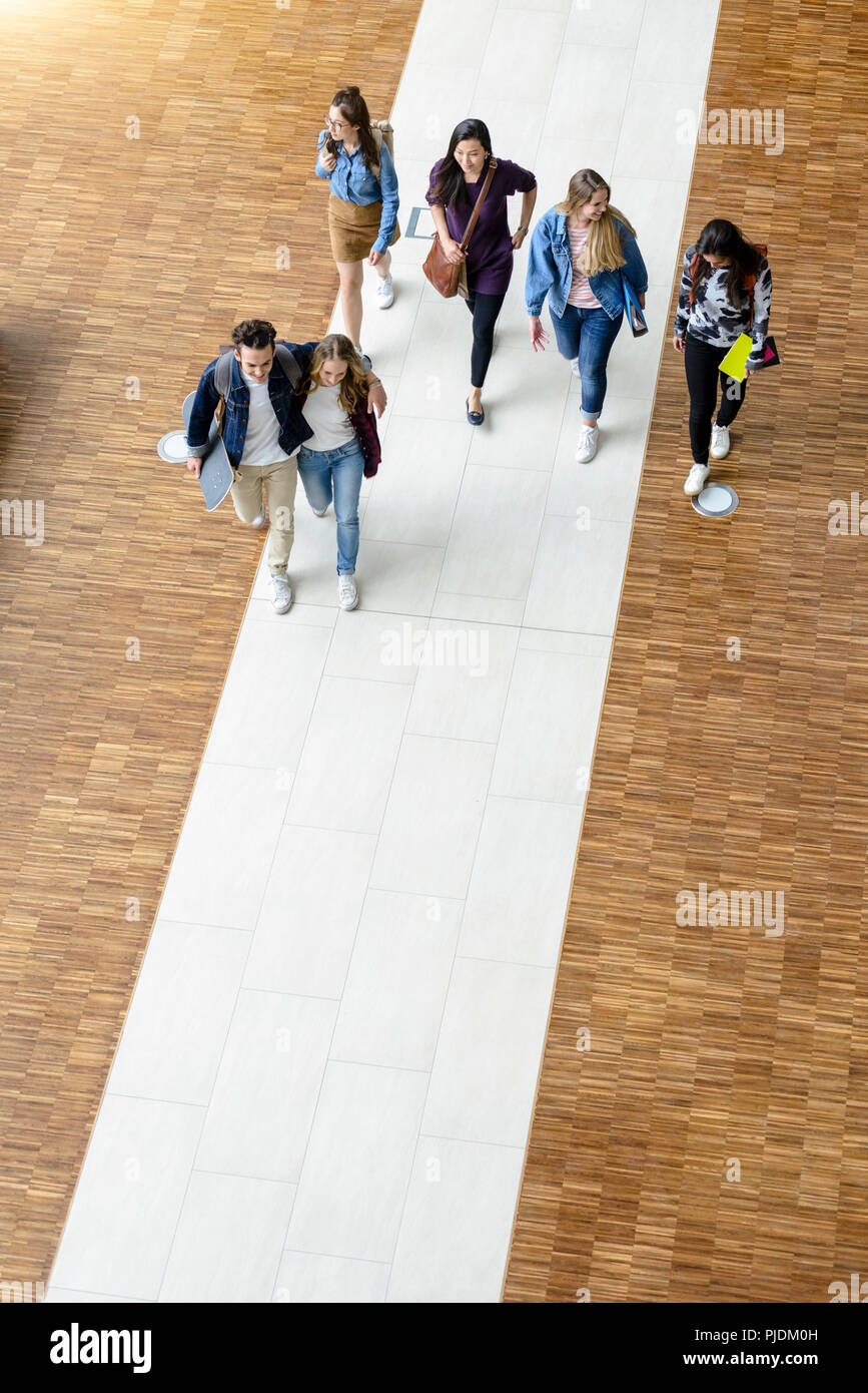 Male and female university students walking and talking in university lobby, high angle view Stock Photo