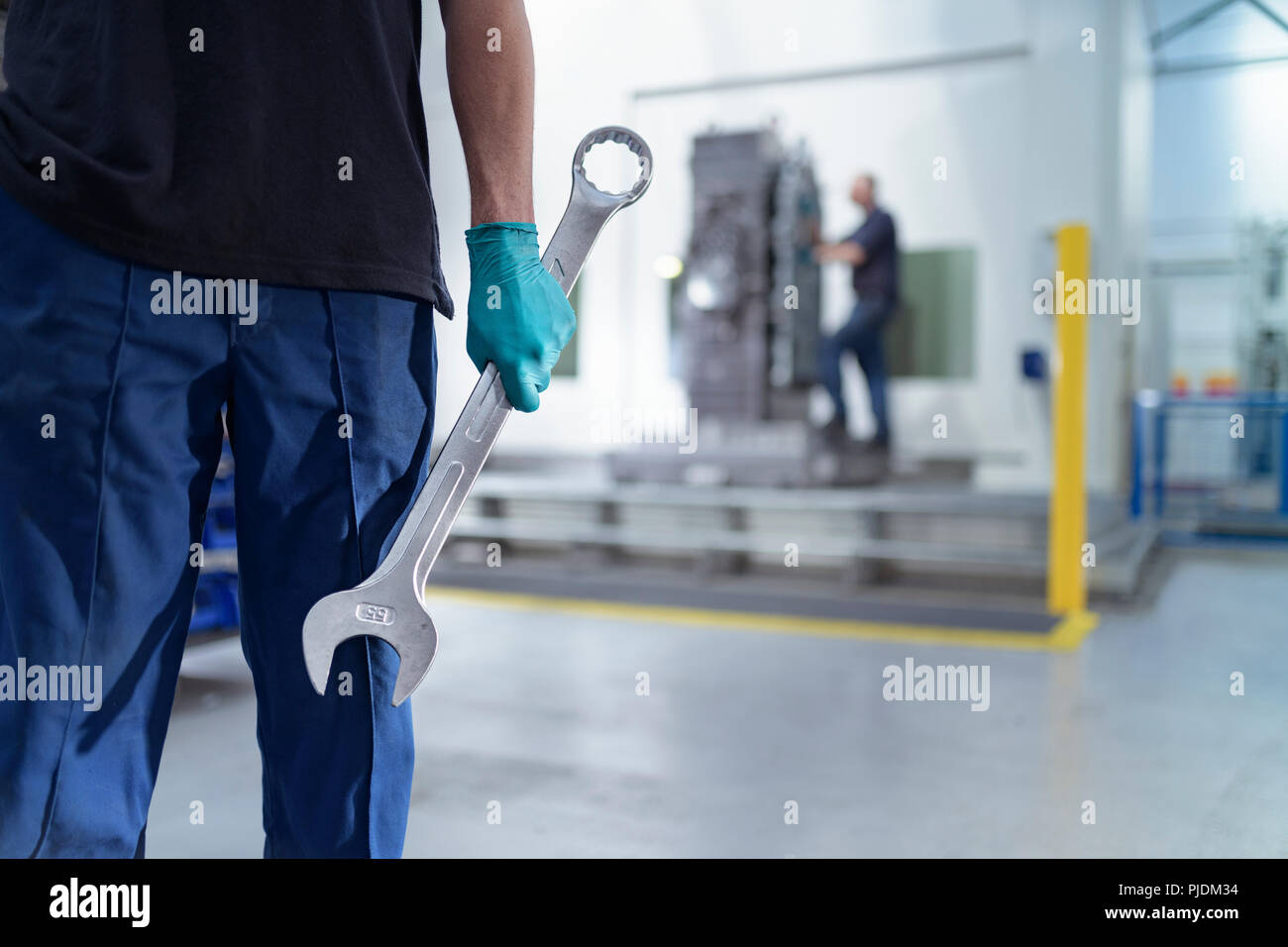 Apprentice engineer holding large spanner in gearbox factory Stock Photo