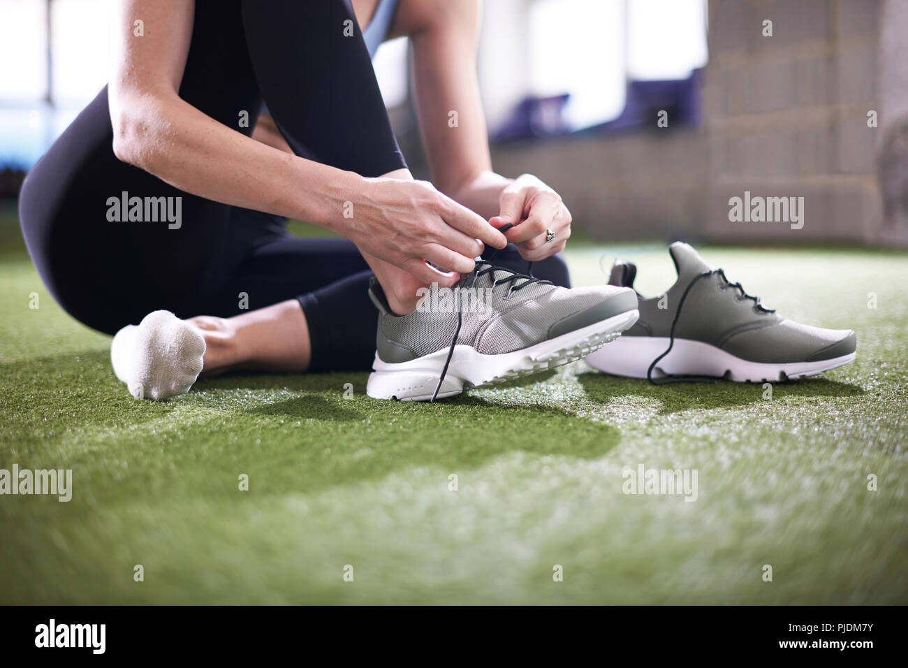 Woman tying shoelace in gym Stock Photo