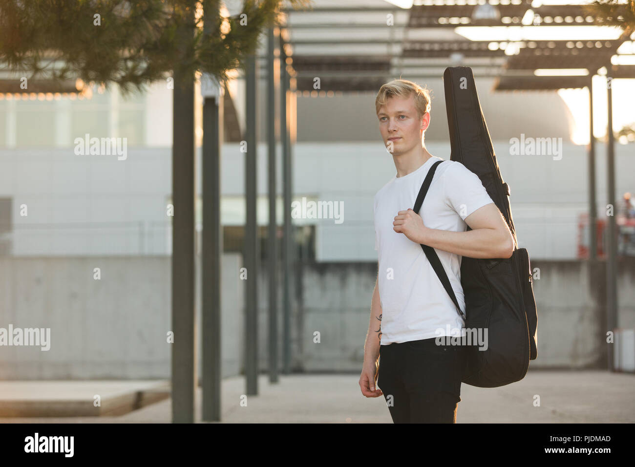 Young musician carrying guitar in case Stock Photo Alamy