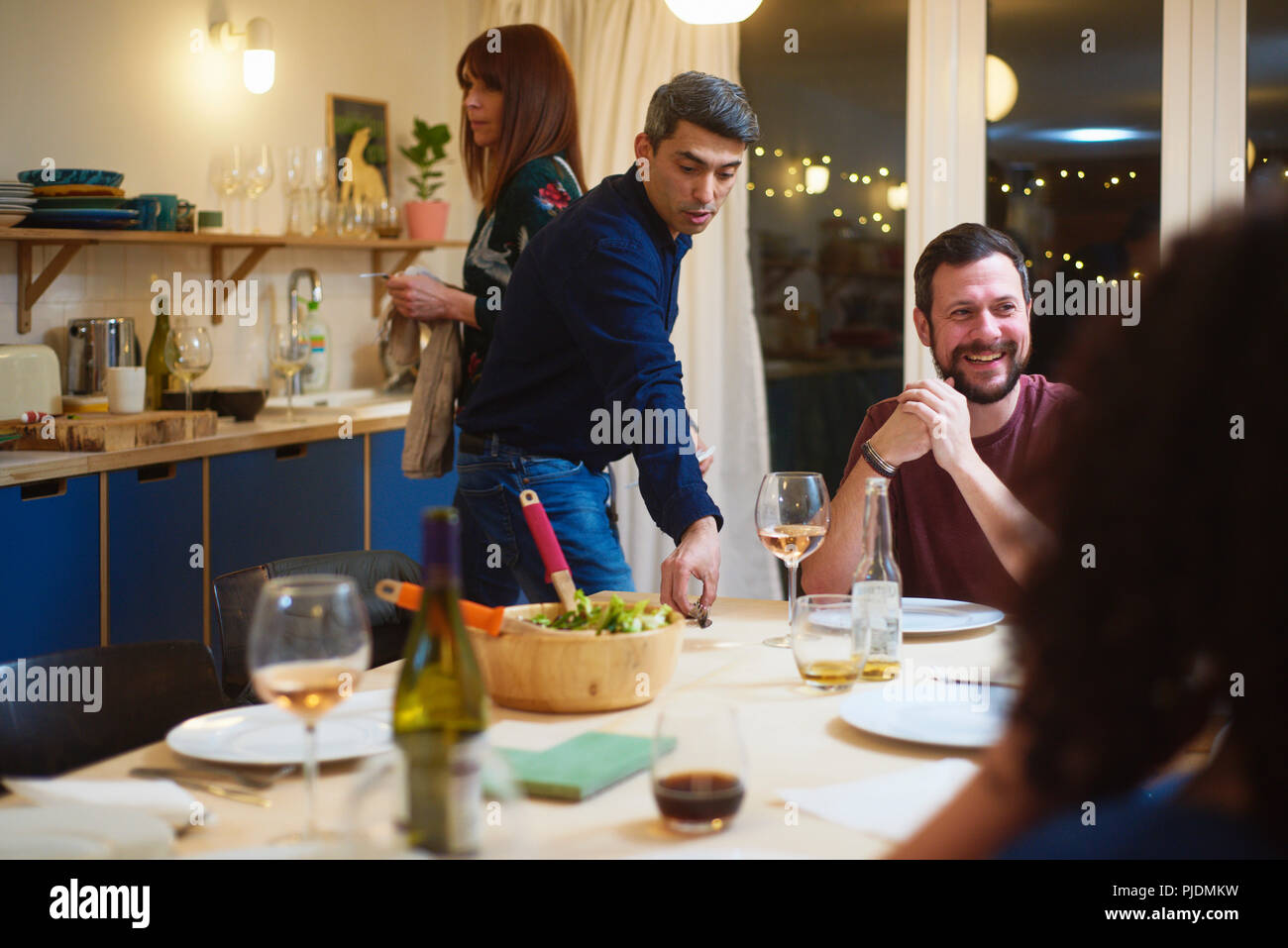 Friends talking, man setting table at dinner party Stock Photo