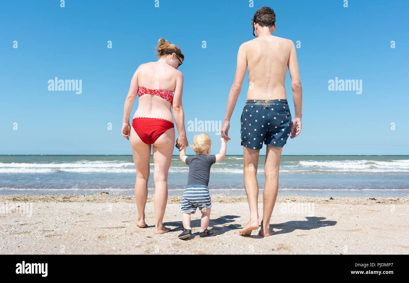 Parents walking with toddler on beach Stock Photo