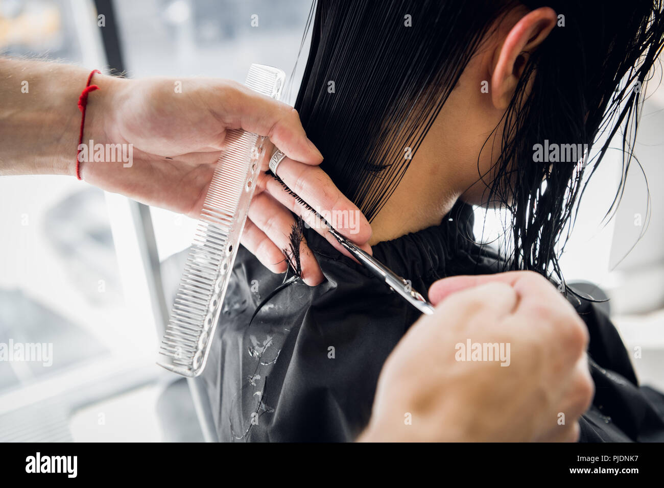 The hairdresser does a haircut with scissors of hair to a young girl in