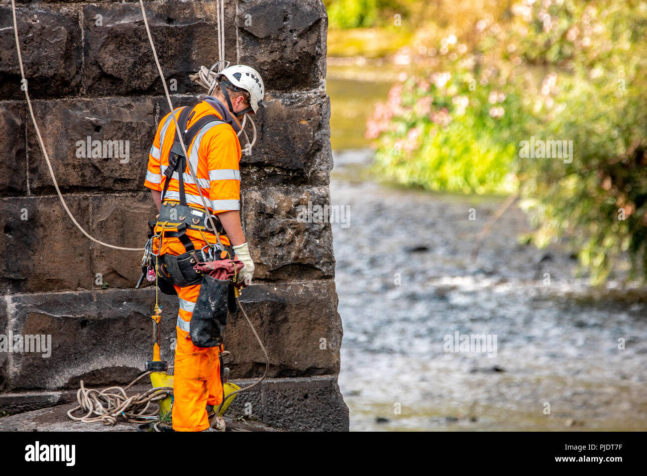 Rail bridge worker attached to safety harness wearing full PPE. Stock Photo