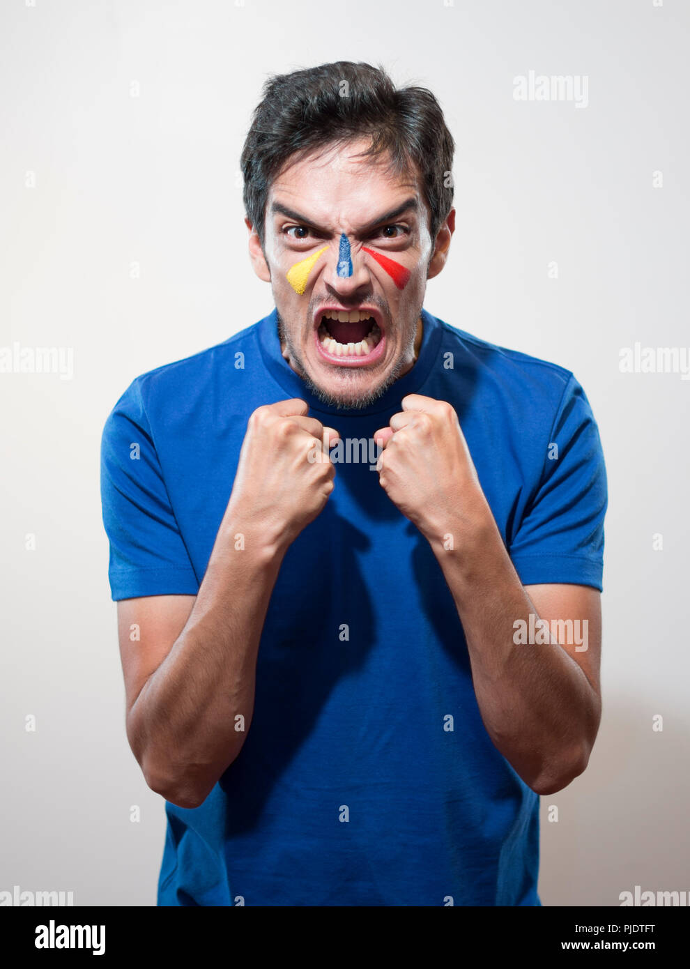 isolted man celebrating goal or victory with his face painted yellow, blue and red Stock Photo