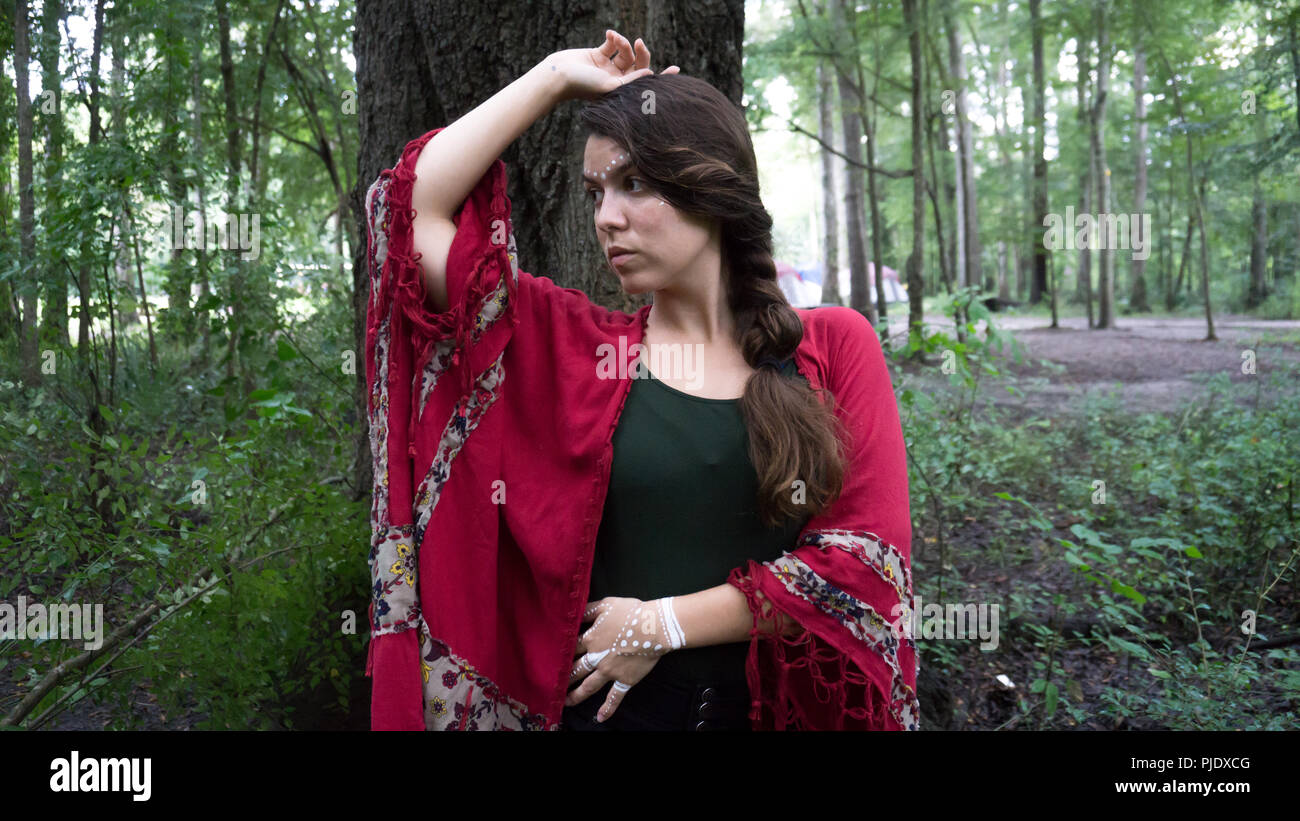 Young hippie beautiful brunette woman with long braid hair next to a tree thoughtful and thinking Stock Photo