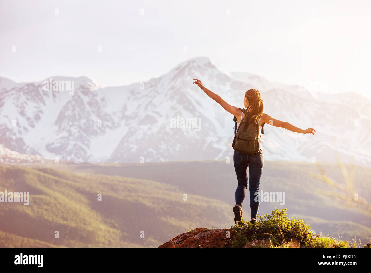 Lady stands big rock against mountains Stock Photo