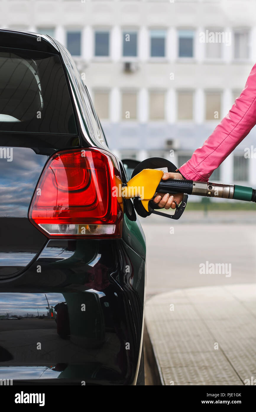 Woman filling up car at petrol station, black car Stock Photo