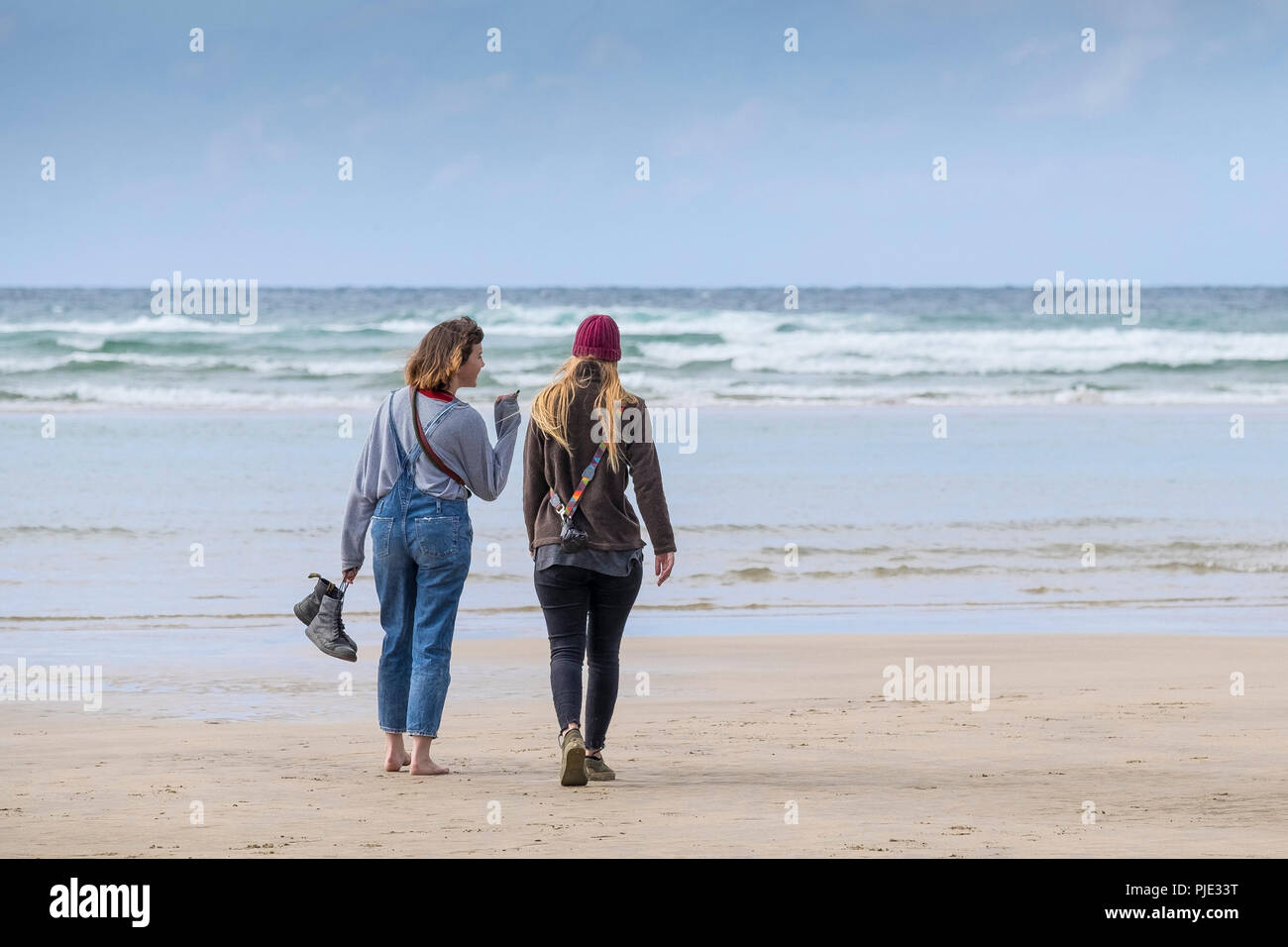 Two friends walking and chatting on Crantock Beach in Newquay Cornwall. Stock Photo