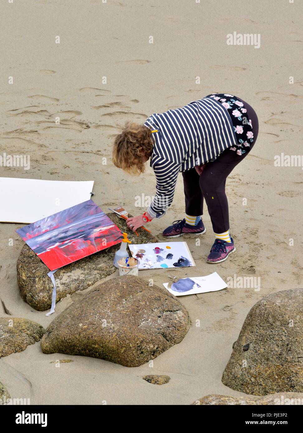 A woman painting on a beach,Sennen Cove, Cornwall,England,UK Stock Photo