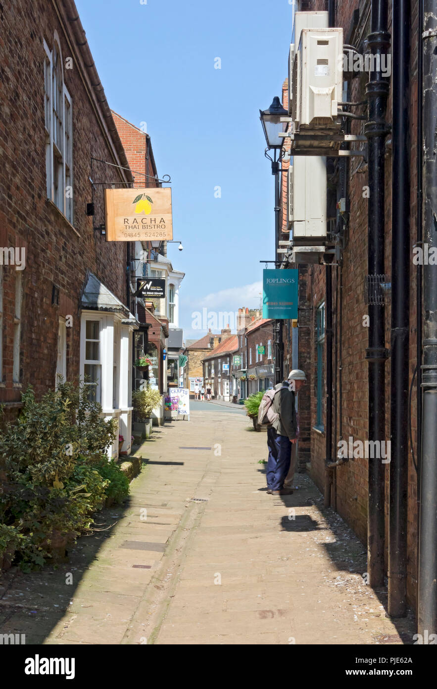 Tourist people looking at a shop store window exterior in summer Bakers Alley Thirsk North Yorkshire England UK United Kingdom GB Great Britain Stock Photo
