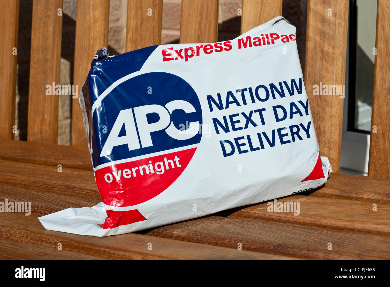 Close up of APC overnight express mail parcel left on bench outside house England UK United Kingdom GB Great Britain Stock Photo