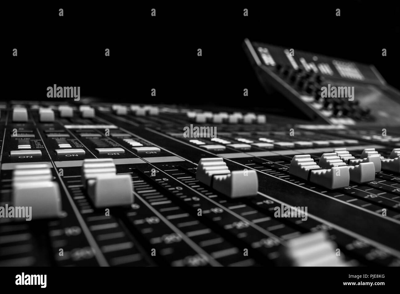 Wide angle closeup of Pro Audio Digital Mixing Console. White Faders and black control Console