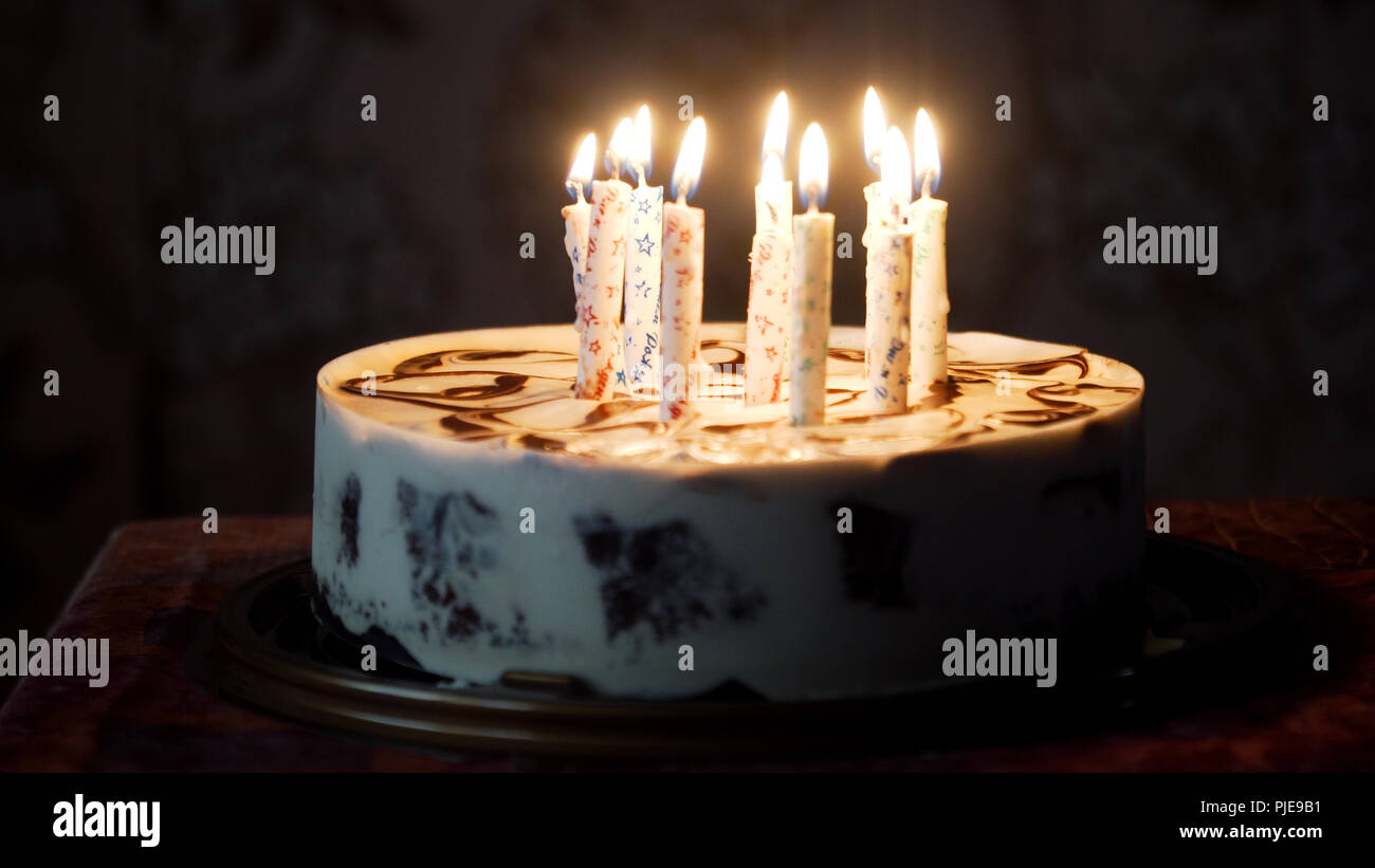Birthday cake with colorful burning candles in dark Stock Photo - Alamy
