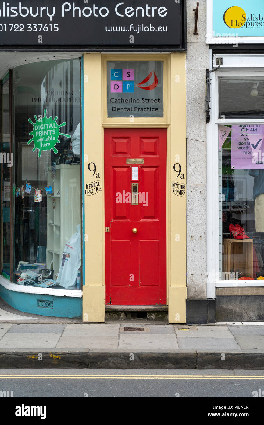 Narrow bright red door entrance to dental practice Stock Photo