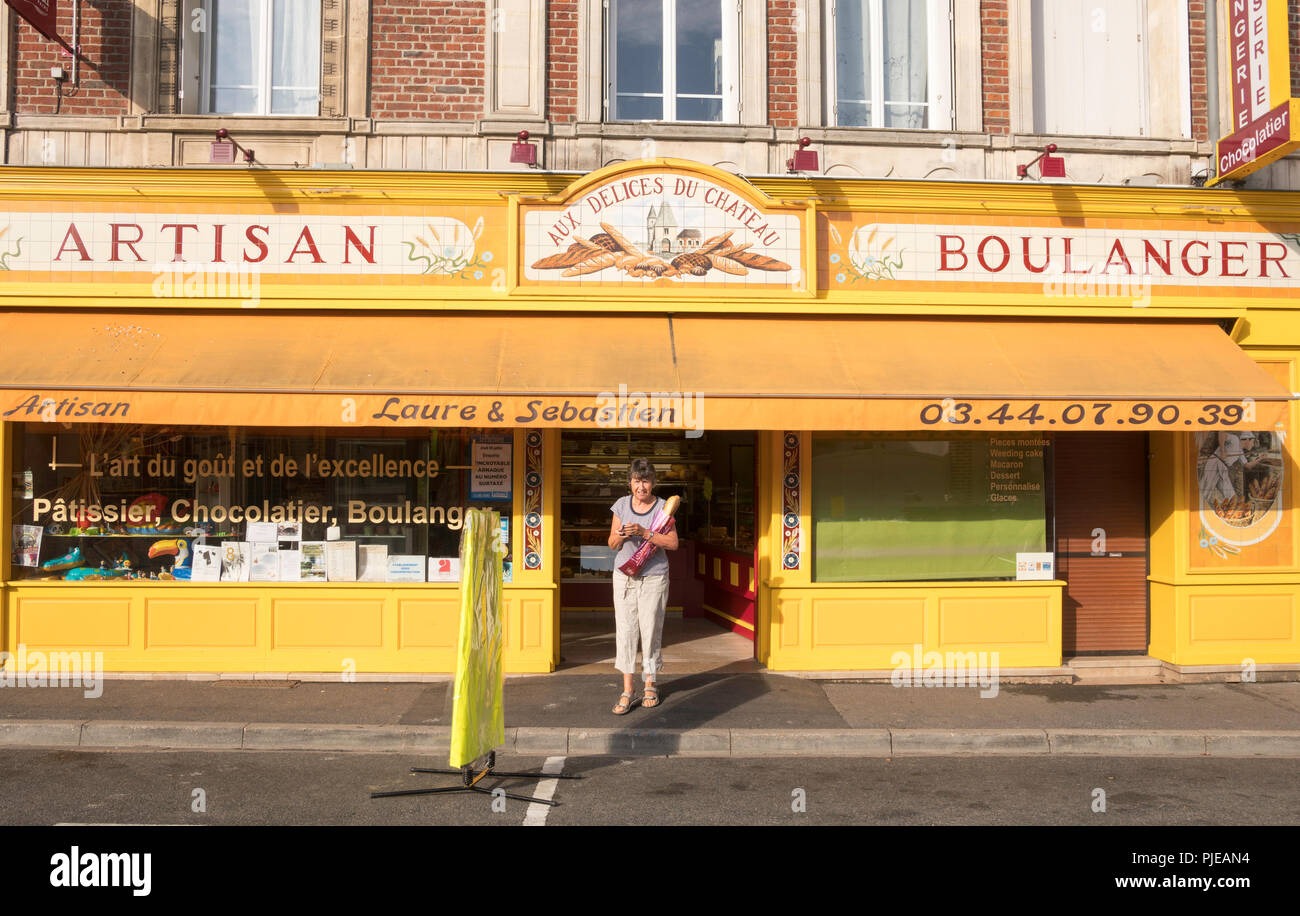 Woman holding baguette outside artisan Boulanger in Bresles, Oise department, France, Europe Stock Photo