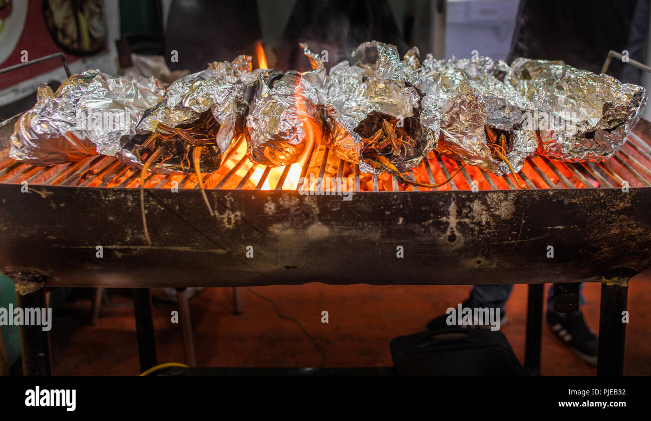 Fresh Langostina (lobster) on the grill from the day's catch, being prepared for diners at Los Kioskos, a street of seafood dining stalls in Galapagos Stock Photo