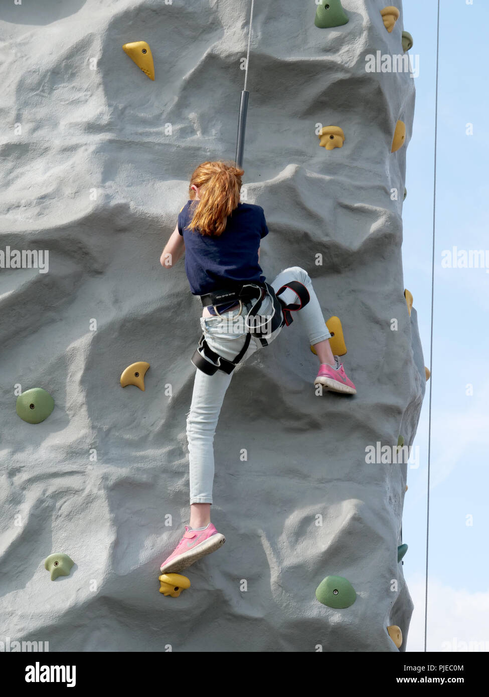 Young girl practicing rock climbing at the Bucks County Show, Buckinghamshire, UK Stock Photo