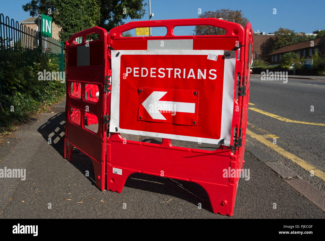red plastic barriers and red and white sign indicating pedestrians should walk to the left at footway works in surbiton, surrey, england Stock Photo
